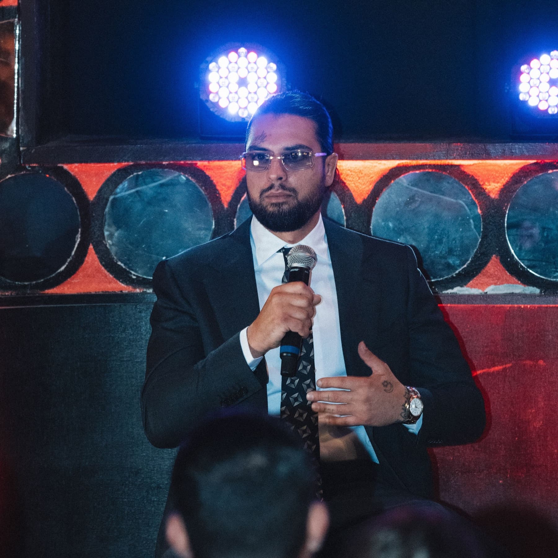 David Chaboki (Shibo / GodsBurnt) in a suit speaking on the Bodega Negra stage at DDNYC 2026 Dog Talk
