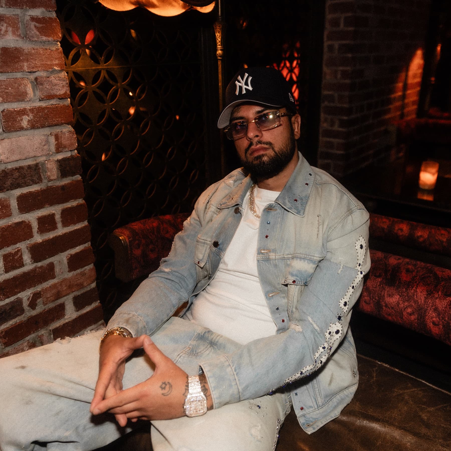 David Chaboki (Shibo / GodsBurnt) seated in crystal denim and a New York Yankees cap at TAO Downtown during DDNYC 2026