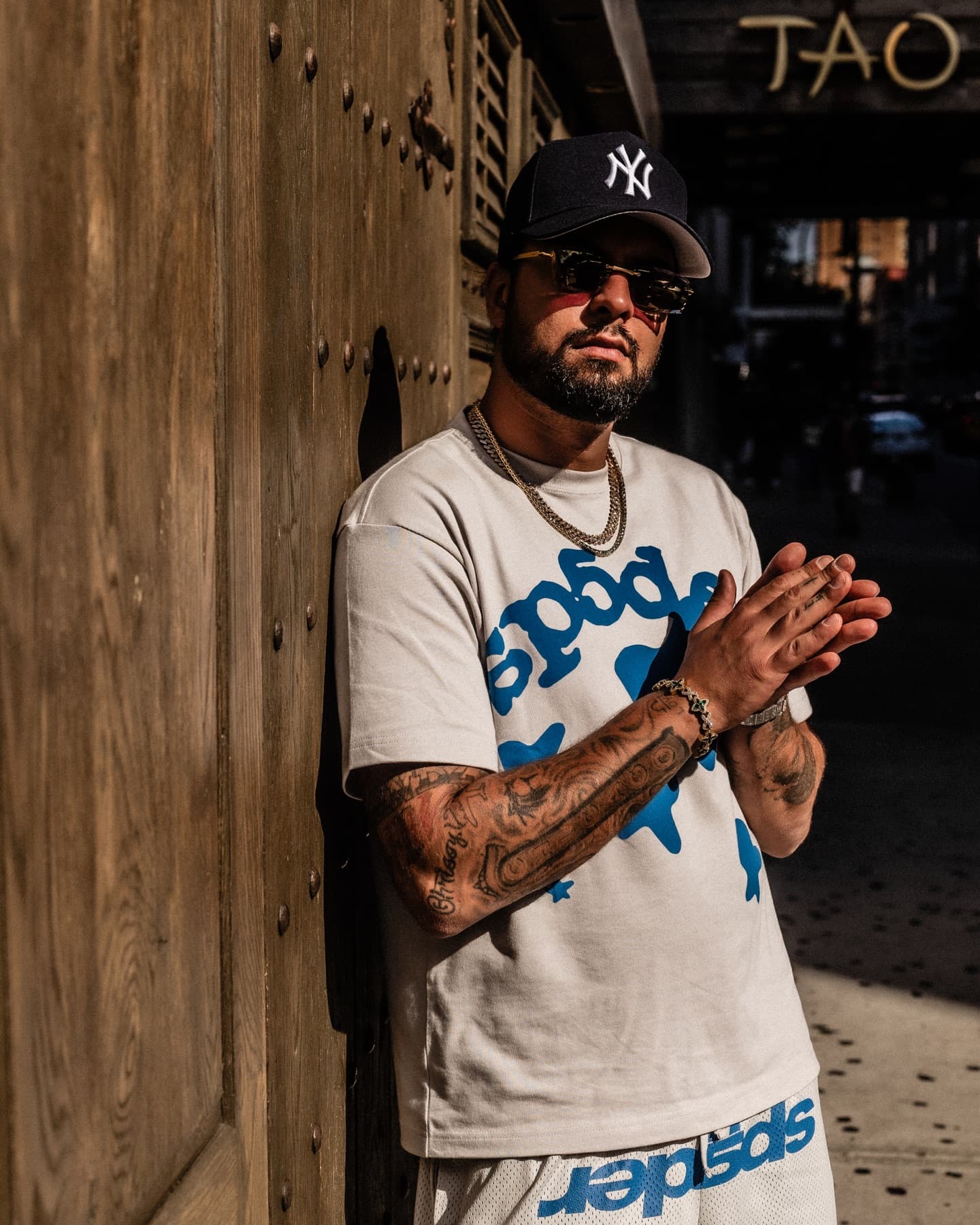 David Chaboki (Shibo / GodsBurnt) street portrait outside TAO Downtown in New York during DDNYC 2026, Yankees cap and gold chains